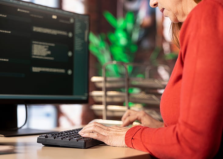 A female employee typing on a keyboard while working in an office.