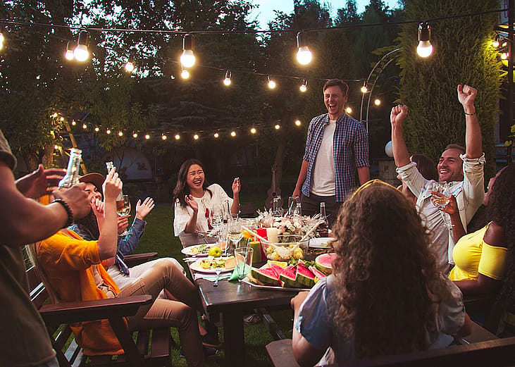 A group of friends laughing together and enjoying their time during a backyard party.