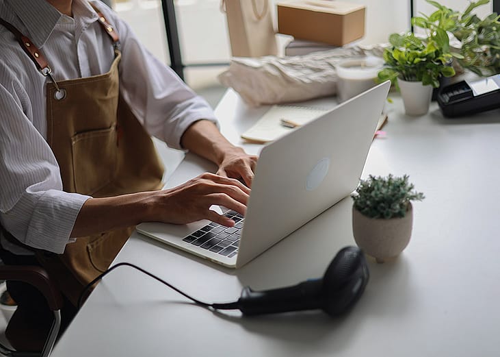 A cafe owner managing online orders from a laptop.