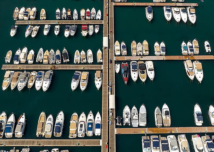 An aerial view of anchored yachts and boats at the docks in a marina.
