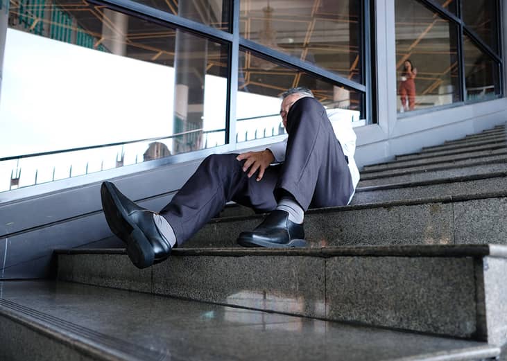 An elderly person getting injured after falling down the stairs in a workplace.