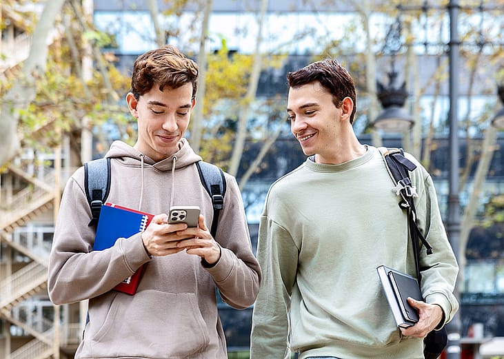 University students checking online content from a smartphone while outdoors in the campus.