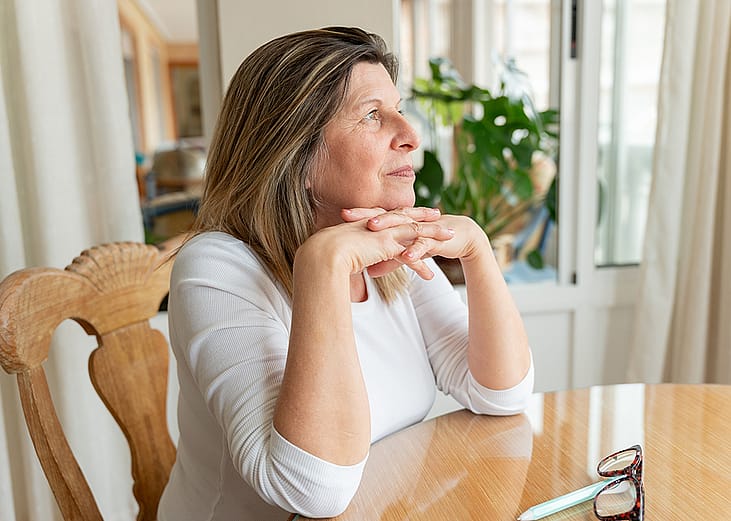A thoughtful senior woman looking out the window.