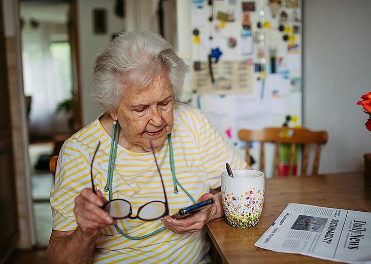 An elderly woman using a smartphone at home.