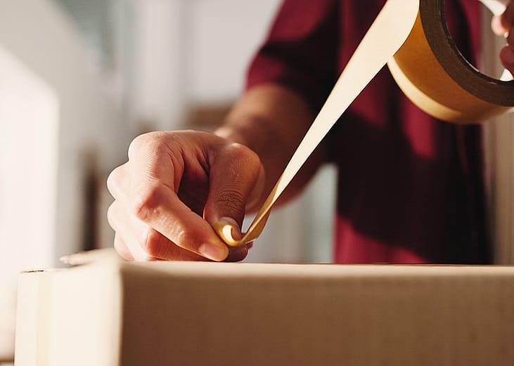 Person taping over a package for shipping.
