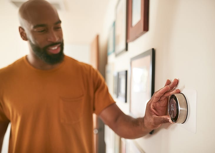 A man adjusting the thermostat at home.