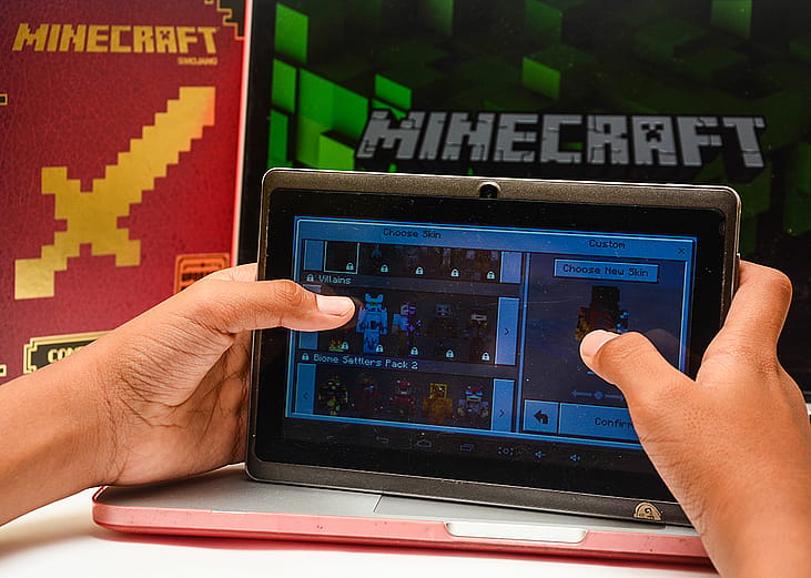 A young child paying Minecraft on a digital tablet.