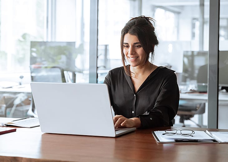 A focused young businesswoman working with a laptop in an office.