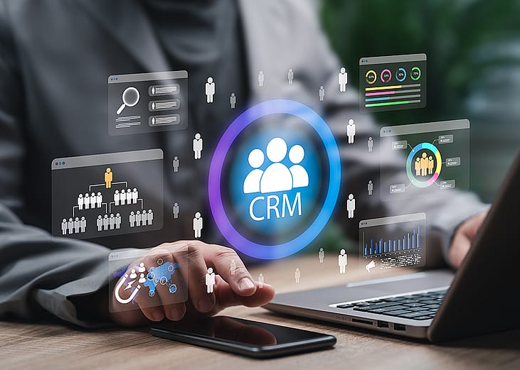 CRM automation graphics over a businessman using a laptop and phone for work.