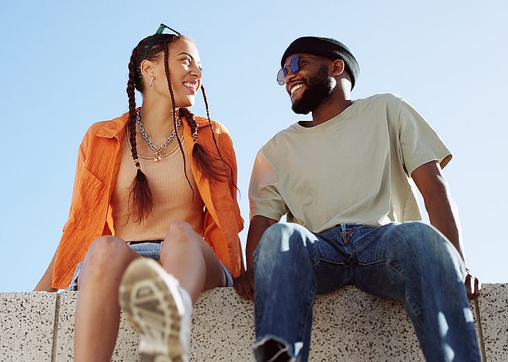 A couple bonding together while enjoying in a sitting wall outdoors.