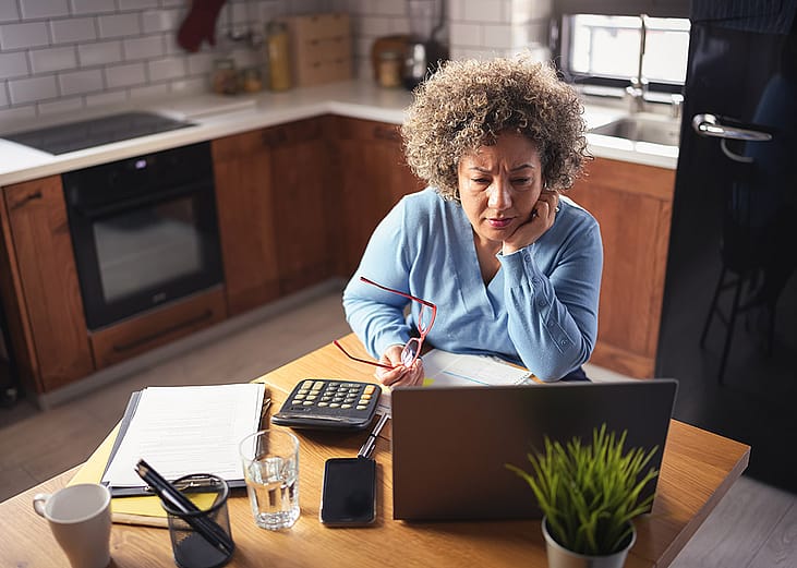 An entrepreneur reviewing budget, expenses, and payments of her business from a laptop.