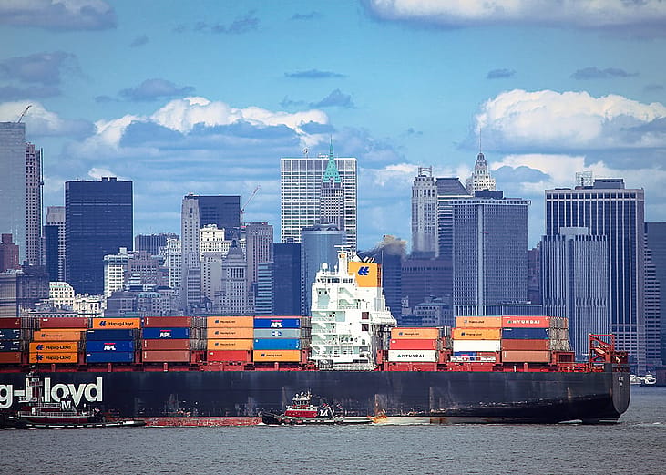 A large container ship carrying imported products entering a port in New York.