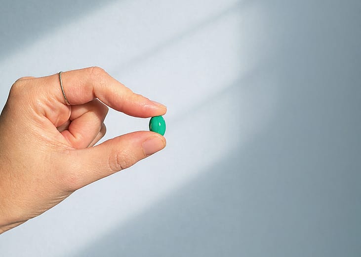 Hand holding a small pill against the sunlight