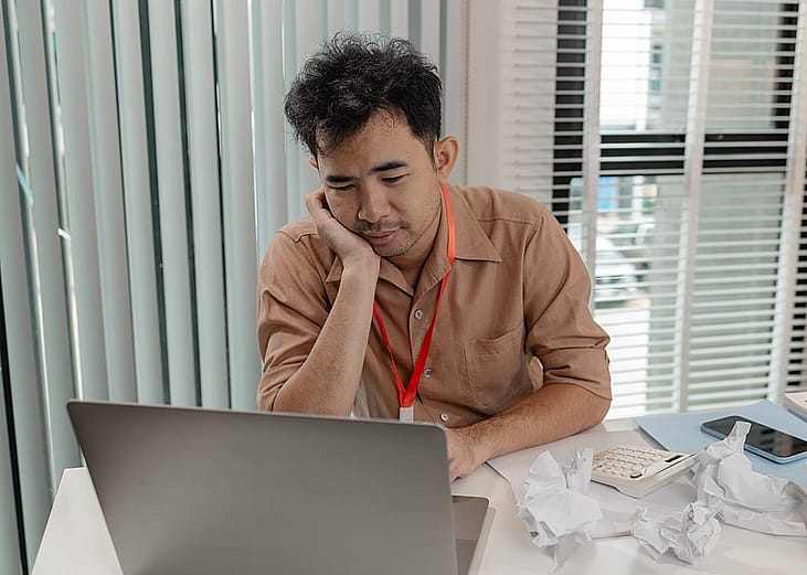 A male employee looking tired at work reviewing reports.