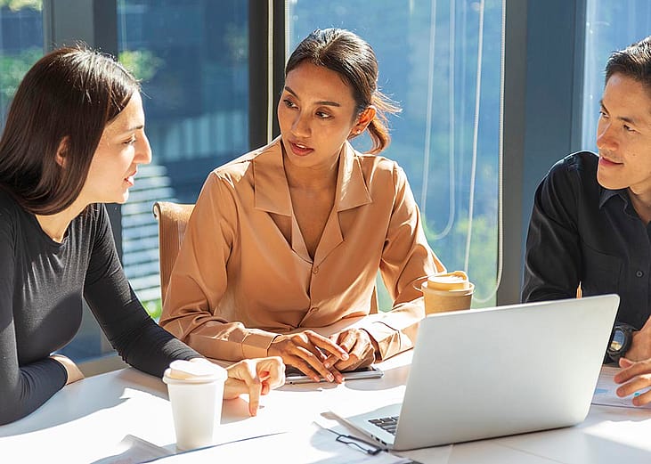A small group of employees discussing work-related matters during a meeting.