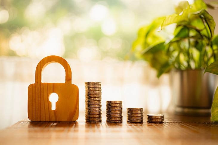A wooden lock model and stacks of coins in descending height. 