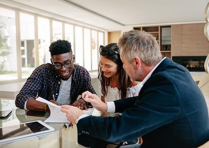 A young couple signing a property contract with a real estate professional.