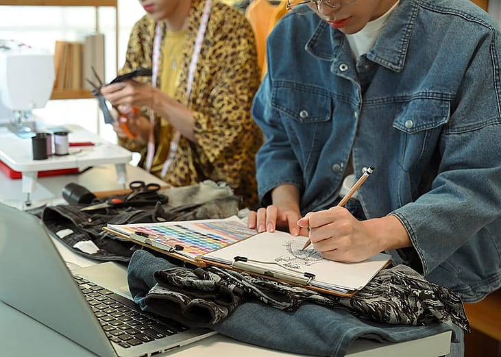 Fashion designers sketching and crafting new clothing designs in their studio.