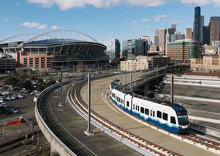 A Sound Transit Link light rail train, with the Lumen field and Seattle skyline in Washington, USA.