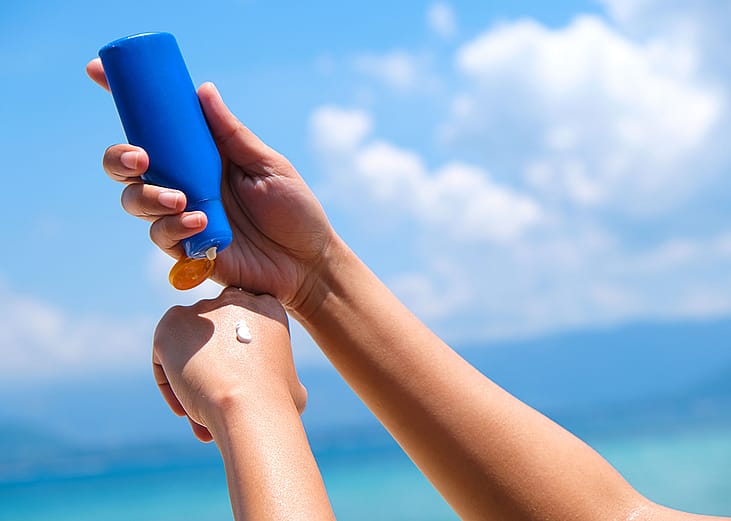 Person putting sunscreen under the sun while at the beach.