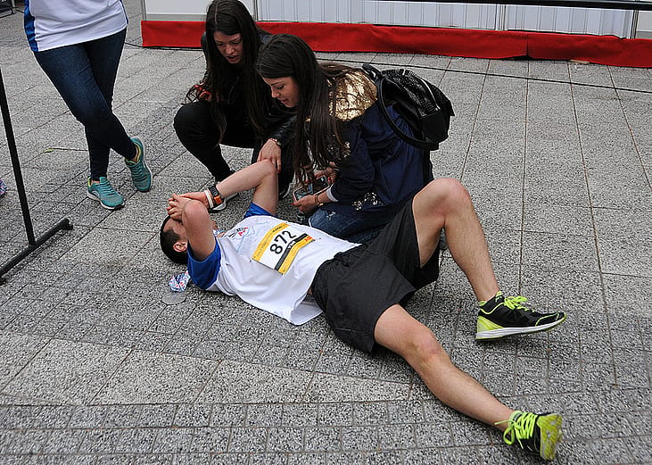 A half-marathon runner collapsing on the ground after crossing the finish line.