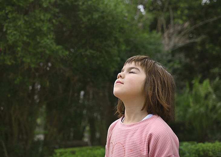 A young girl breathes fresh air outdoors.