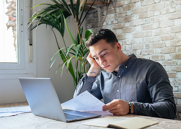 A young adult reviewing an official loan document for personal finance matters.