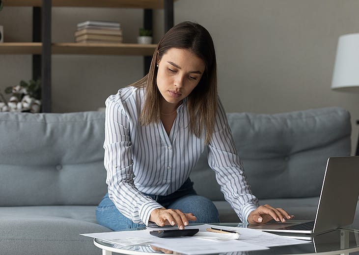 A focused woman at home reviewing financial reports.