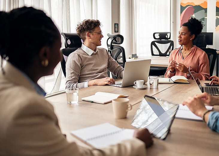 A diverse group of business professionals engaged in a discussion in a meeting room.