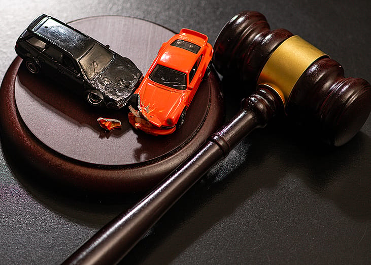 Figures of crashed cars and a gavel as a concept of traffic court civil litigation.
