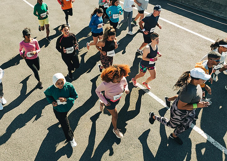 Aerial view of a diverse group of participants running in an organized outdoor race. 