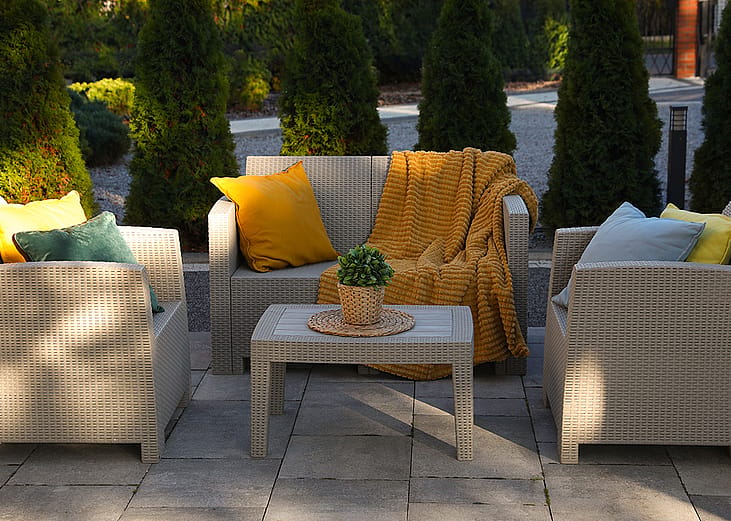 An outdoor rattan garden furniture set with yellow and cream motifs.