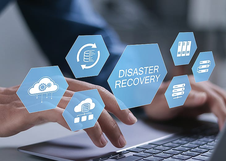 Businessman typing over a keyboard illustrated with conceptual graphics for a cyber disaster recovery system.