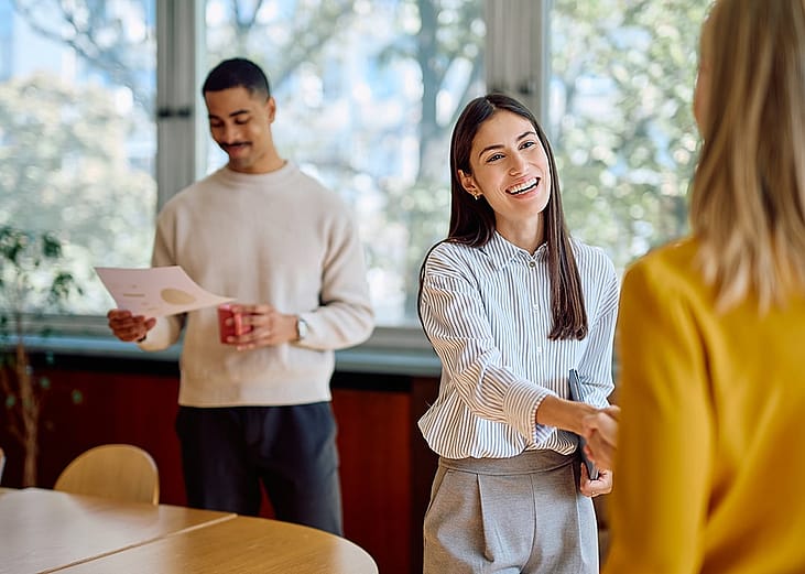 A businesswoman enthusiastically shaking hands with a new coworker.
