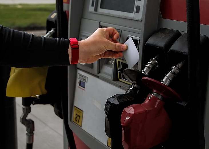 Person tapping credit card onto a gas station payment reader.