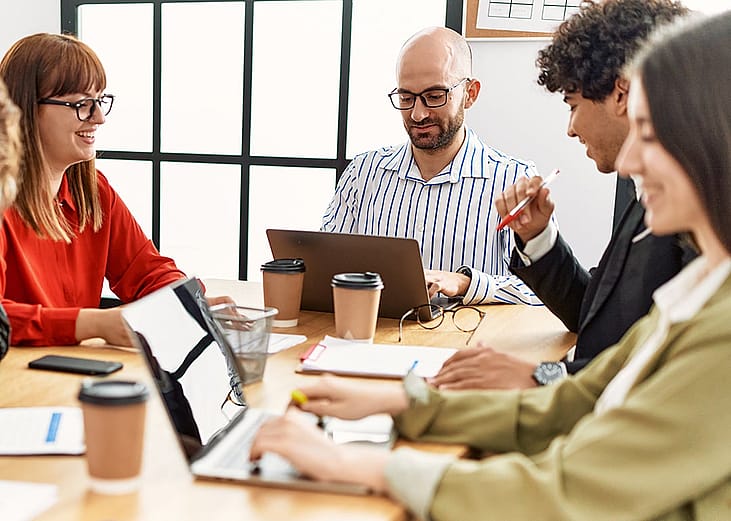 A group of coworkers happily engaged in a team meeting.