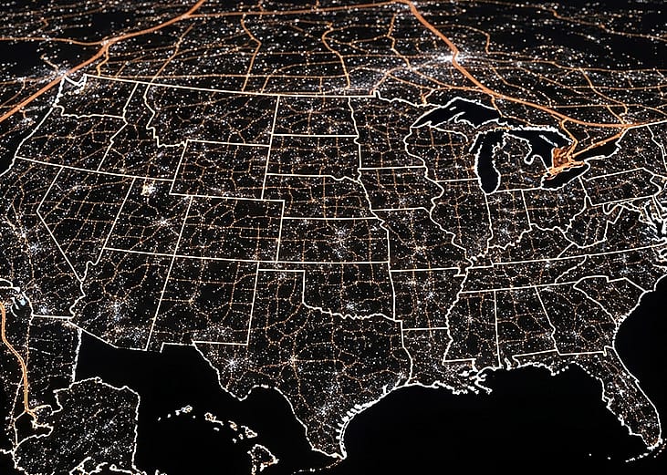 A view of the United States of America at night, highlighted by city lights.