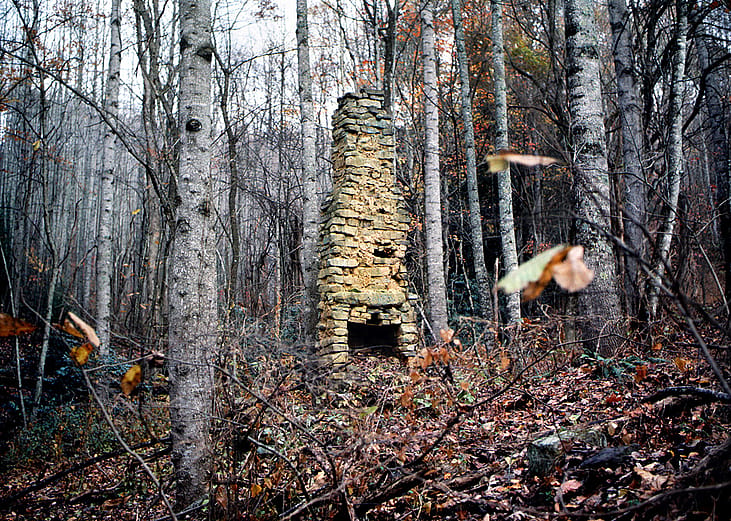 A stone chimney is seen from a 19th century log cabin located in the Appalachian Mountains in Northern America.
