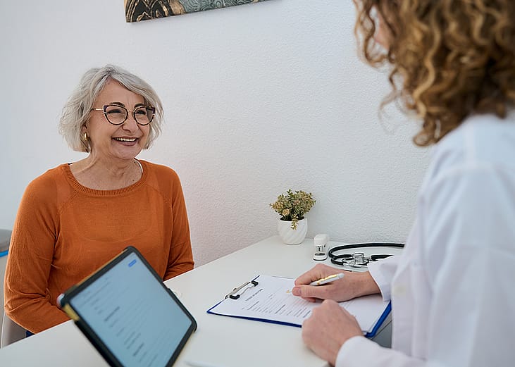 A happy senior woman talking to her doctor during a health appointment.