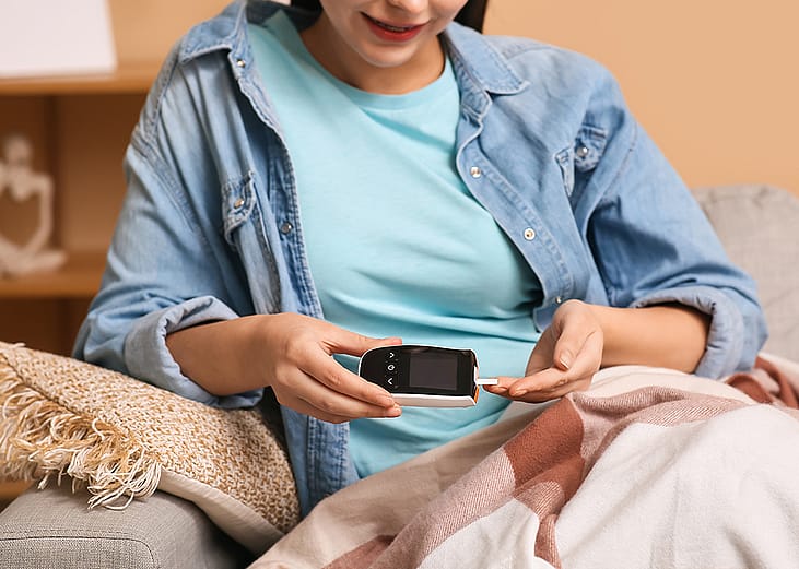 A young diabetic woman measuring blood sugar level at home.