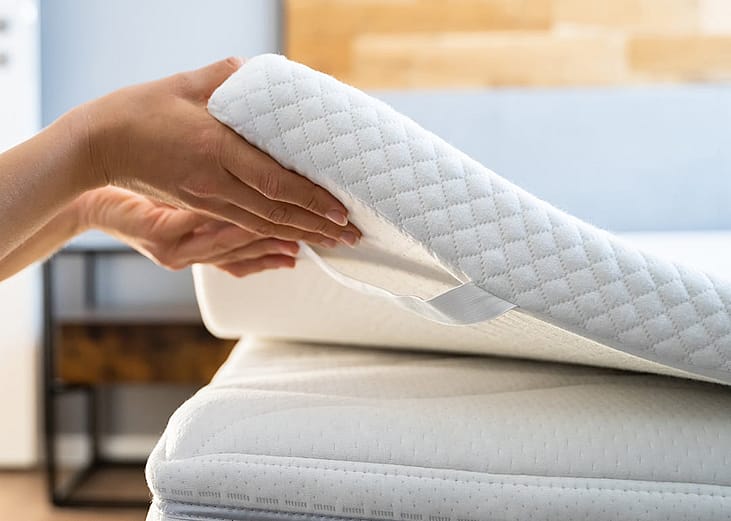 A mattress topper being put on top of a bed. 