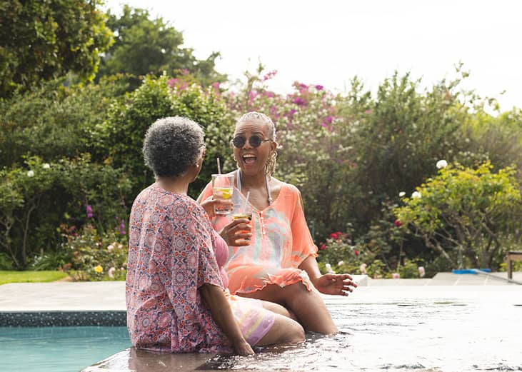 Two retired women having drinks and enjoying their time in a pool.