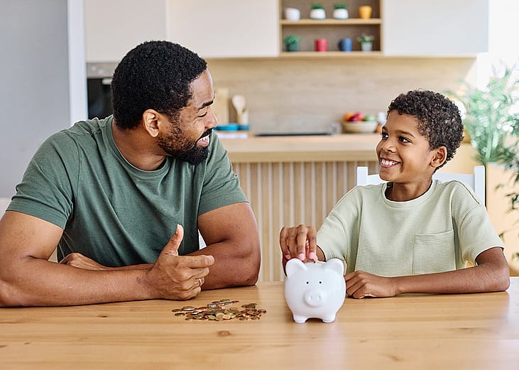 A father teaching his young son to save money in a piggy bank.