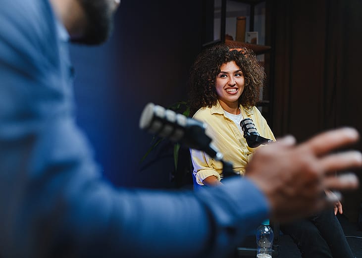 Two podcast hosts happily engaging in discussion for their recording session.