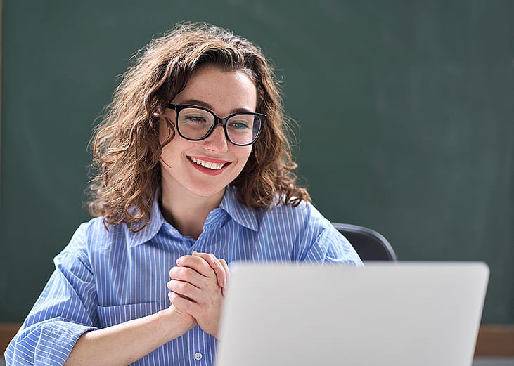 A teacher looking excited while reading good news online.
