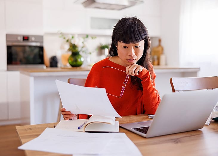An anxious woman reviewing her bills at home.