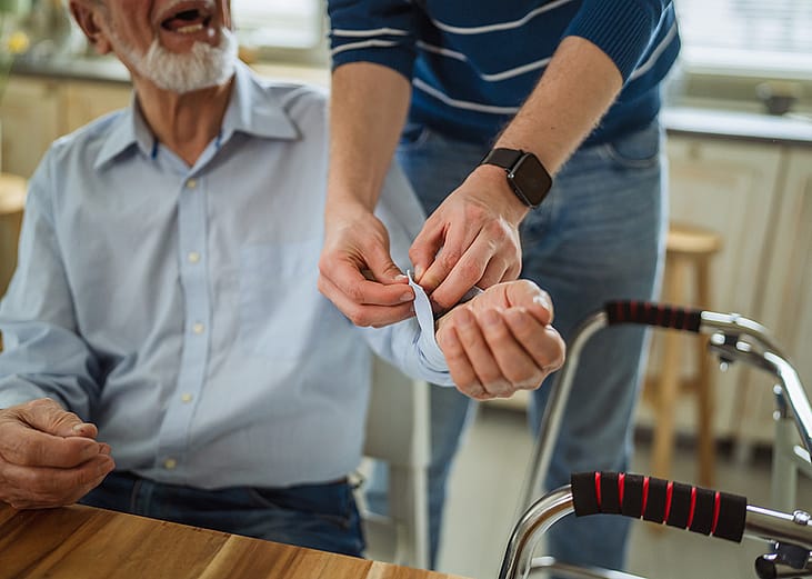 A home caregiver assisting an elderly person before checking the patient's blood pressure.