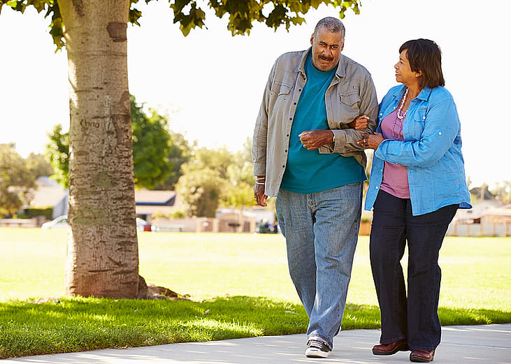 An elderly couple walking together in a park.