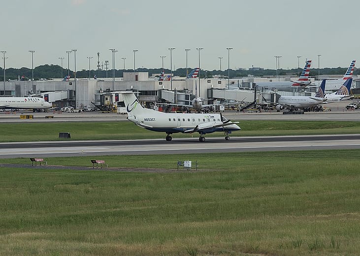 Airplanes are landing and taking off at the runway at the Charlotte Douglas International Airport with the city of Charlotte, North Carolina.