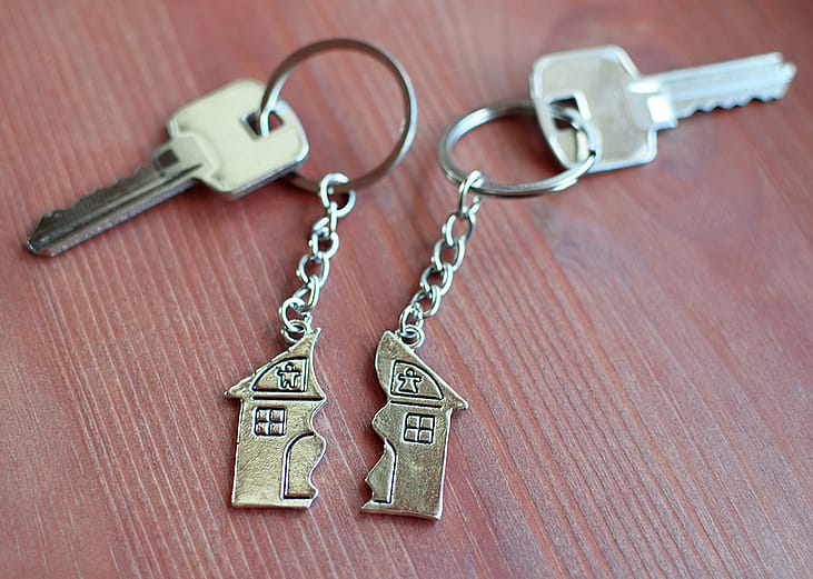 Two keys with split house pendants laid in a wooden background.